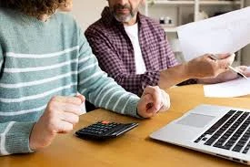 Household budgeting with calculator, documents and laptop