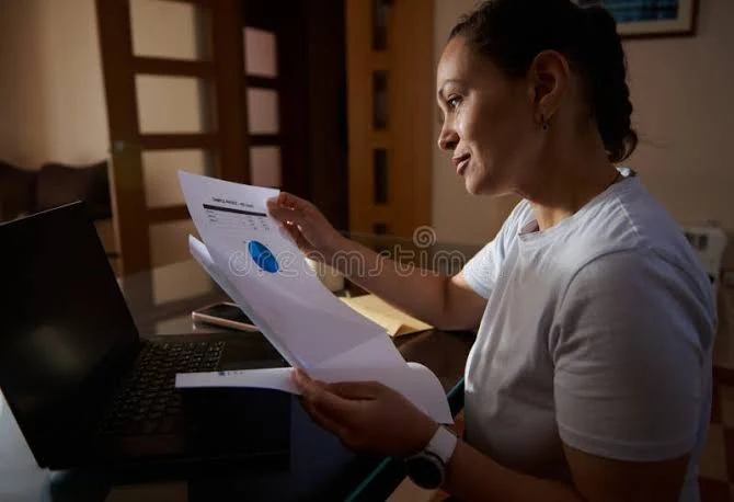 Reviewing financial paperwork and debt planning at a laptop